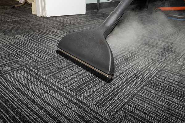 Close up of black office carpet getting cleaned with steam