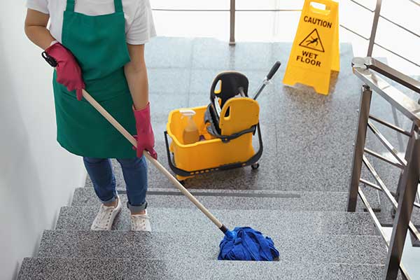 Janitor mopping up a gray, modern commercial staircase