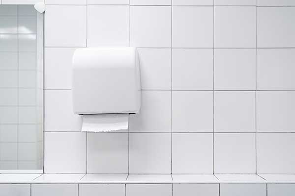 White tiled bathroom with a paper towel dispenser