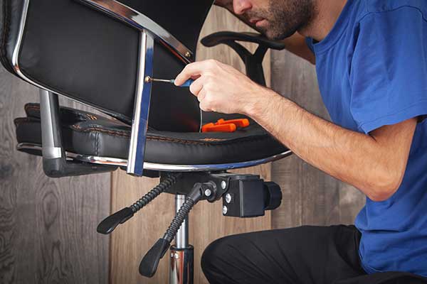 Handyman assembling and fixing up an office chair