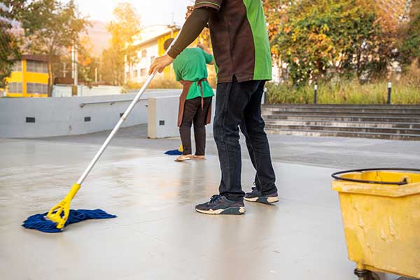 Two janitors mopping up an exterior commercial walkway area